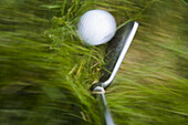 GOLF Blurred motion of club and golf ball in heavy grass on course in Deerfield,  Illinois