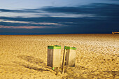2 garbage cans,  at dusk on a beach on the North sea,  Belgium.
