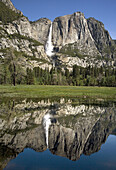 YOSEMITE FALLS IS REFLECTED IN AN OVERFLOW POND OF THE MERCED RIVER DURING THE SPRING SNOWMELT IN YOSEMITE NATIONAL PARK,  CALIFORNIA