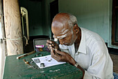 A watch repairer (old man) sitting in front of an agraharam house (brahmin house) in Konerirajapuram near Kumbakonam,  Tamil Nadu,  South India,  India.