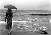 Young woman standing under cloudy sky