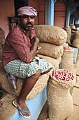 A porter resting on bags of shallots  Kollam,  Kerala,  India