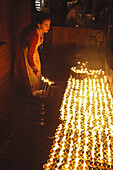 A woman dumping out butter candles at Boudhanath Stupa Kathmandu,  Nepal