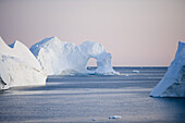 View at iceberg with hole at Ilulissat Kangerlua Isfjord at dusk, Disko bay, Kitaa, Greenland