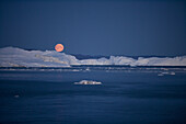 Full moon rising over icebergs from Ilulissat Kangerlua Icefjord at dusk, Ilulissat (Jakobshavn), Disko Bay, Kitaa, Greenland