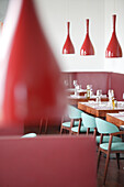 Modern restaurant with red lamps and turquoise chairs