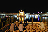 Golden Temple at night and praying Sikhs, Sikh holy place, Amritsar, Punjab, India, Asia