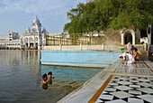 Golden Temple, two young Sikh men bathing in the holy lake, Sikh holy place, Amritsar, Punjab, India, Asia