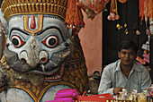 Händler verkauft Opfergaben neben steinernem Löwen am Jagannatha Tempel, Puri, Orissa, Indien, Asien
