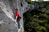 A young man climbing at Mgarr Ix-Xini rocks, Flakeout Walls, Gozo, Malta, Europe