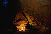 Two men enyoing a campfire near sandstone rock, Palatine Forest, Rhineland-Palentine, Germany