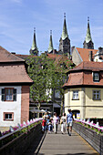 Fussgänger auf der Regnitzbrücke und die vier Türme des Dom, Bamberg, Oberfranken, Bayern, Deutschland