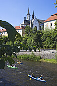 Canoers on the Vltava river with the Cistercian monastery Vyssi Brod in the back, South Bohemian Region, Czech Republic