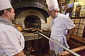 Cooks preparing roast lamb in a wood-fired oven, La posada de la Villa, Cava Baja, Madrid, Spain