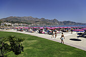 Leute sonnen sich am Strand, Golf von Giardini Naxos, Taormina im Hintergrund, Sizilien, Italien