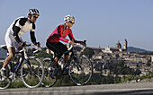 Young man and young woman cycling, Urbino, Le Marche, Italy