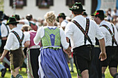 Couples wearing traditional costumes passing meadow, May Running, Antdorf, Upper Bavaria, Germany