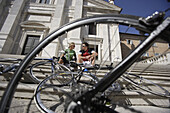 Junges Paar mit Fahrrädern rastet auf den Stufen vor einem Haus, Urbino, Marken, Italien, Europa
