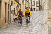 Young couple riding bicycles on a street at San Leo, Marche, Italy, Europe