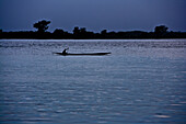 Man paddling in dug out canoe on the river Niger in the evening, Sagou, Mali, Africa