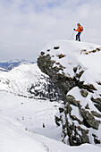 Woman back country skiing, standing on a rock, Staffkogel, Saalbach-Hinterglemm, Kitzbuehel range, Salzburg, Austria