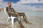 Woman smeared with mineral mud sunbathing, Dead Sea, En Bokek, Israel, Middle East