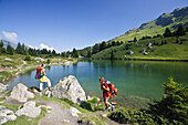Zwei Frauen wandern an einem Bergsee, Alp Flix, Sur, Graubünden, Schweiz