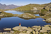 Woman hiking along lakes Flueeseen at Stallerberg, Juf, Grisons, Switzerland