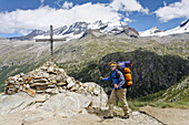 Hiker near summit cross, Croix de la Roley, Gran Paradiso in background, Valsavarenche, Gran Paradiso National Park, Aosta valley, Italy