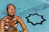 Woman sitting next to the swimming pool of Spa Riad Mehdi, Marrakech, Morocco, Africa