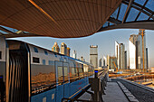 Neue Metro vor Skyline des Finanzzentrums von Dubai an der Zeihet Road