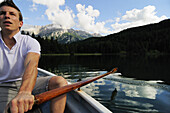 Young man rowing, lake Lautersee, Mittenwald, Werdenfelser Land, Upper Bavaria, Germany