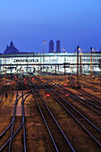 Schienen und Bahnhofsgebäude, beleuchtet, Frauenkirche und Justizpalast im Hintergrund, Hauptbahnhof München, München, Oberbayern, Bayern, Deutschland