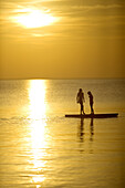 Silhouettes of children playing on a stonewall in the sea