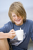Long haired boy with a cup