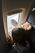 Boy looking through airplane window, Munich airport, Bavaria, Germany