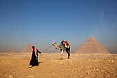 Touristenführer mit Kamel vor der Pyramide des Mykerinos (links) und der Chefren Pyramide (rechts), Gizeh, Kairo, Ägypten, Afrika