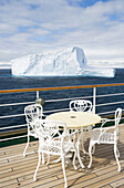 Tisch und Stühle an Deck von Kreuzfahrtschiff MS Deutschland (Reederei Deilmann) mit Blick auf antarktische Eisberge, Südliche Shetlandinseln, Antarktis