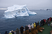 Passagiere an Deck von Kreuzfahrtschiff MS Deutschland (Reederei Deilmann) betrachten antarktischem Eisberg, Südliche Shetlandinseln, Antarktis