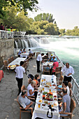 Menschen in einem Restaurant neben der Selalesi-Wasserfälle bei Manavgat, Südküste, Türkei