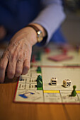 Monopoly-Spiel mit Würfeln und Häusern, Hand einer Spielerin, Unschärfe, Spielgeld, Deutschland