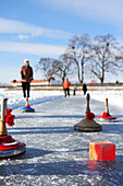Ice stocks with daube, group of people and Nymphenburg castle out of focus in the background, Nymphenburg castle, Munich, Upper Bavaria, Bavaria, Germany