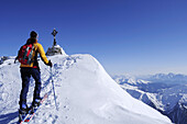 Woman backcountry skiing, summit cross in the background, Magerstein, Rieserferner range, South Tyrol, Italy
