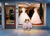 2 girls standing at window looking at gowns dreaming about a dance