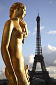Gilded bronze statues decorating the central square of the Palais de Chailot with Eiffel Tower in background, Paris. France