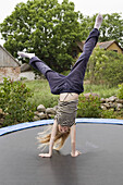 Girl standing on her hands on a trampolin.