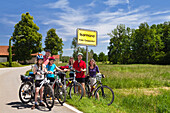 Cyclists beside a town sign, Isarmuend, Isar Cycle Route, Lower Bavaria, Germany