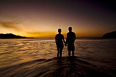 Silhouette of young couple holding hands on the beach while watching the sunset in Playas del Coco, Costa Rica
