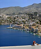 Woman sitting in front of the sweeping view of the island town of Symi Greece
