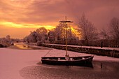 A festively decorated boat frozen in the ice at Coolnahay Harbour, Co. Westmeath, Ireland, during the Christmas season.